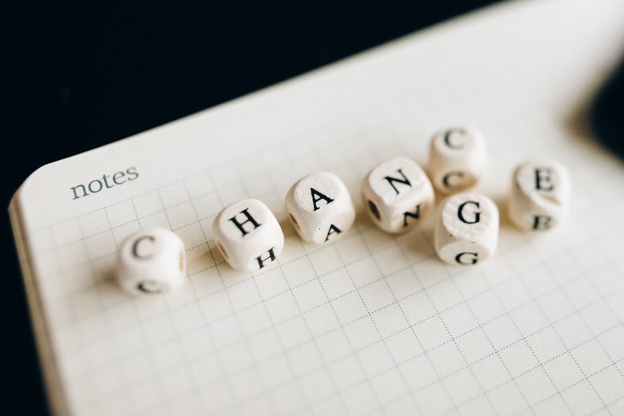 Close-up of letter dice spelling 'change' on a grid notepad, symbolizing transformation.