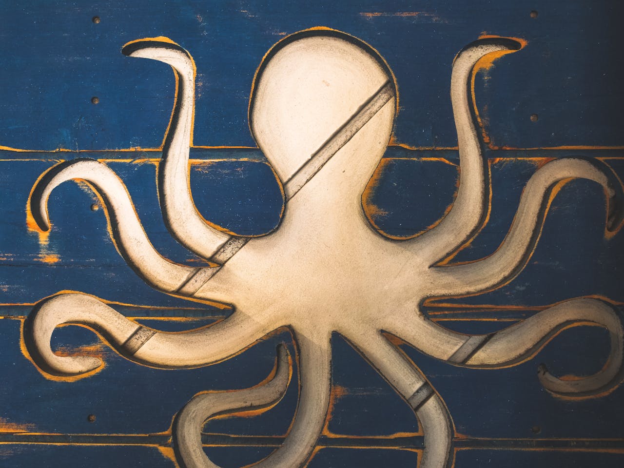 Detailed close-up of a wooden octopus sculpture on a blue panel, showcasing handcrafted artistry.